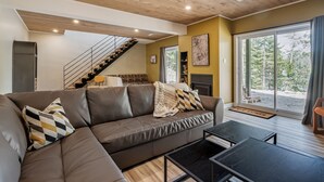 A modern living room with a brown leather sofa, a black coffee table, and a staircase leading to an upper level.
