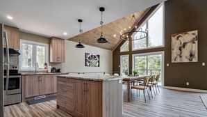 A modern kitchen with wooden cabinets, a large island, and pendant lighting.