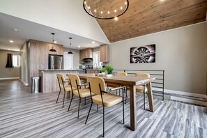 Eine moderne Küche mit Holzschränken, Edelstahlgeräten und einem Essbereich mit Holztisch und -stühlen.