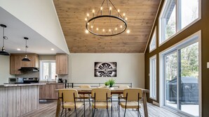 A modern kitchen with wooden cabinets, a central island, and a dining area with four chairs and a table.