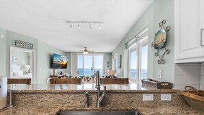 A kitchen with granite countertops, stainless steel faucets, and a large window overlooking the ocean. - 🌞Beachfront|Gulf Views|Pools|3BR Summerwind 804🌞 (Navarre Beach)