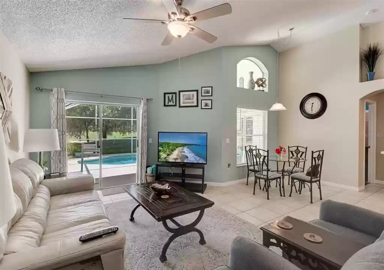 Una sala de estar con un sofá, una mesa de centro, un televisor y un comedor con sillas y una mesa.