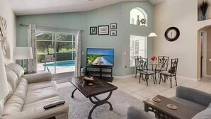 Una sala de estar con un sofá, una mesa de centro, un televisor y un comedor con sillas y una mesa.