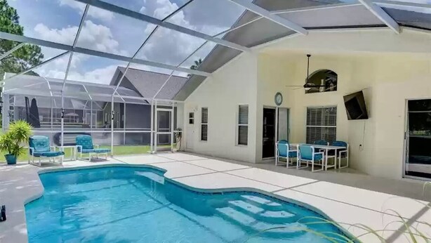 Una piscina exterior techada con techo de vidrio, rodeada de sillas de descanso y una zona de patio.