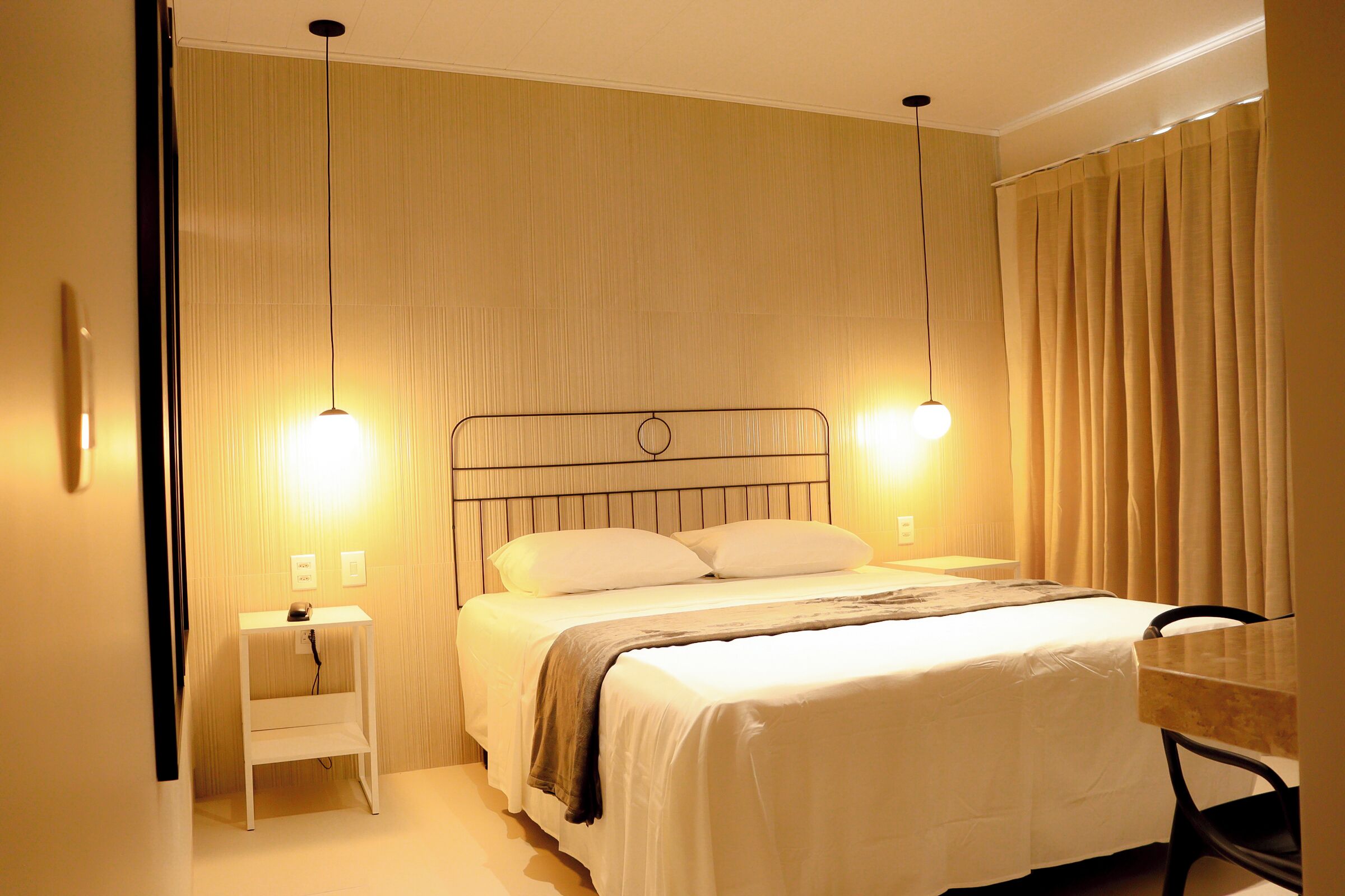A hotel room with a bed, bedside tables, and a desk.