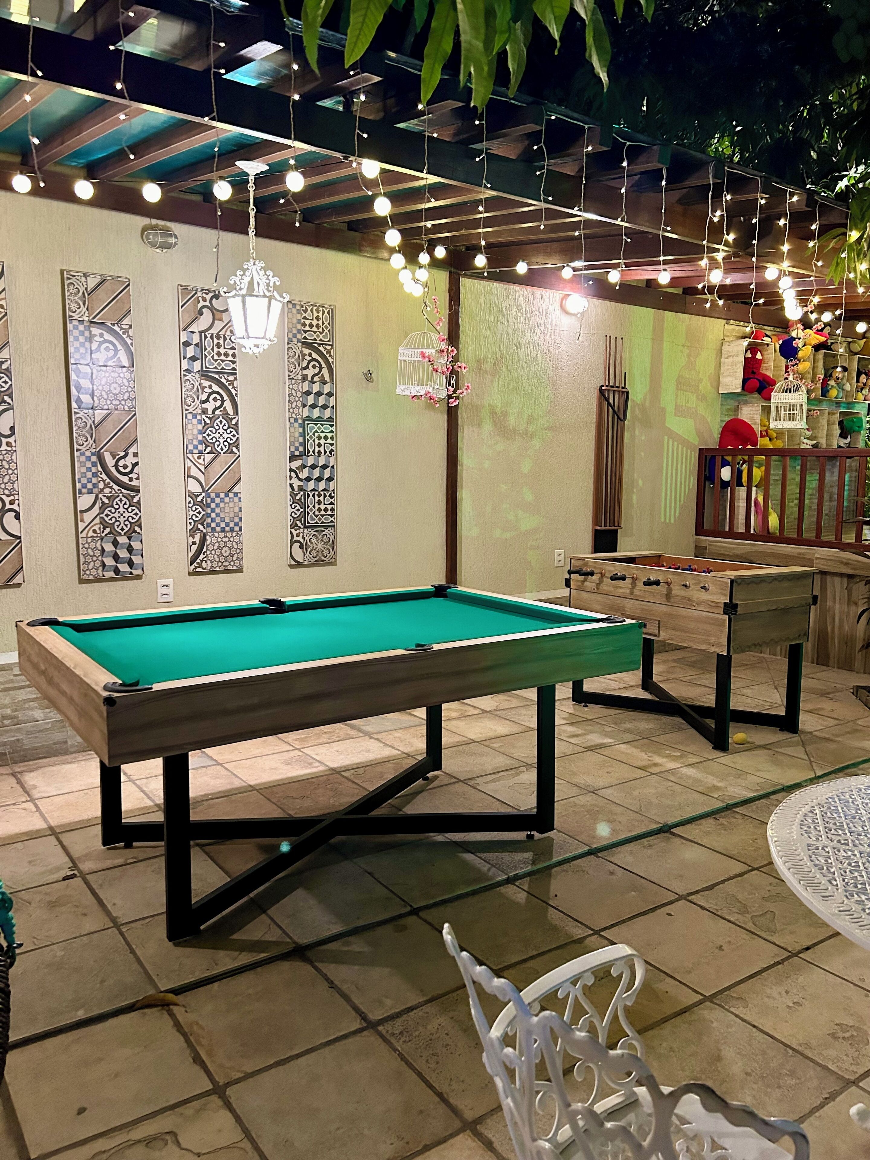 A pool table in a room with patterned walls, a wooden ceiling, and hanging lights.
