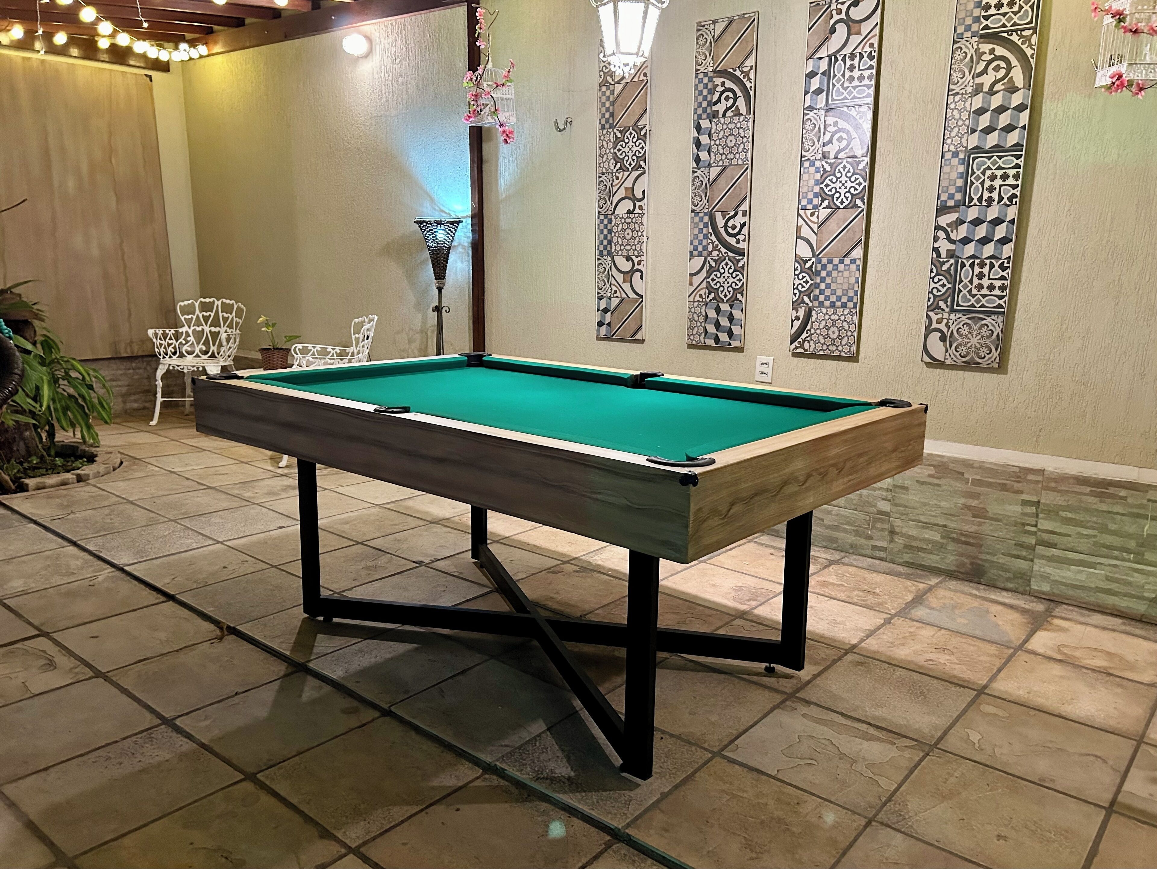 Une table de billard dans une pièce aux murs décorés de motifs et au sol carrelé.