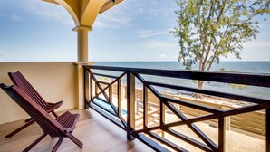 Un balcon doté de balustrades en bois, d’un plancher en bois et offrant une vue sur la mer et la plage.