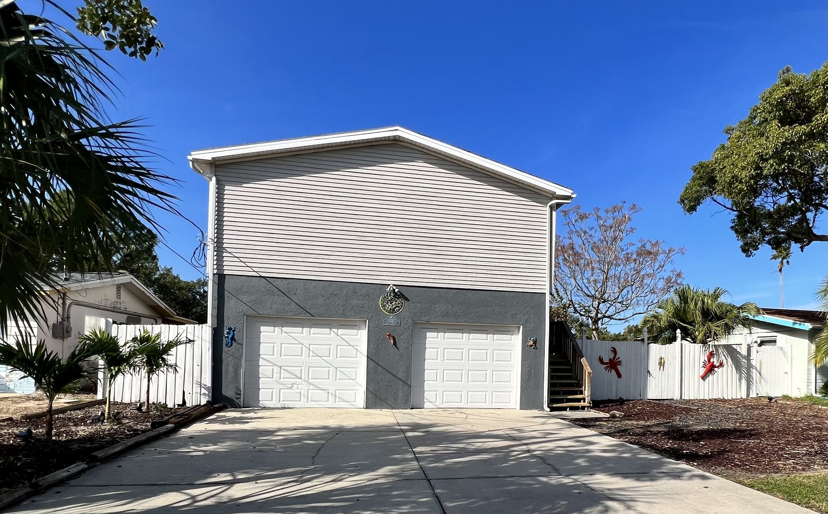 Une maison à deux étages avec un garage, un petit porche et une cour clôturée.