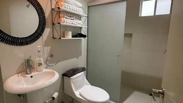 A bathroom with a sink, toilet, and shower area.