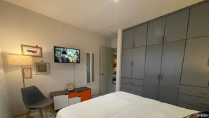 A bedroom with a bed, a TV, a wardrobe, and a desk. - Condo en Residencial con Alberca (Durango)