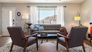 Un salon comprenant un canapé, deux fauteuils, une table basse et un ventilateur de plafond.