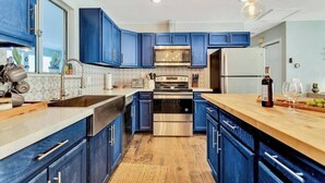 Une cuisine moderne avec des armoires bleues, des appareils en acier inoxydable et un comptoir en bois.