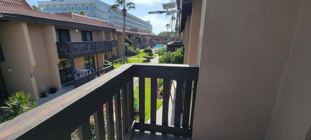A hotel balcony with a view of a landscaped garden and other hotel buildings.