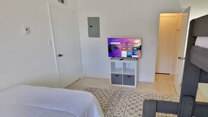 Une chambre d’hôtel comprenant un lit, un téléviseur posé sur un meuble, une armoire et une porte donnant sur une autre pièce.
