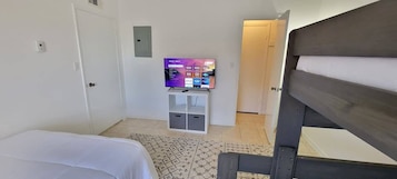 A hotel room with a bed, a TV on a stand, a wardrobe, and a door leading to another room.