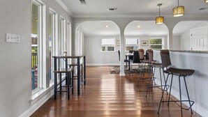 A spacious kitchen with a long counter, bar stools, and a view of the backyard. - Beautifully Renovated Waterfront House in Gulfport (Gulfport)