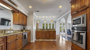 A spacious kitchen with wooden cabinets, stainless steel appliances, and a central island. - Beautifully Renovated Waterfront House in Gulfport (Gulfport)