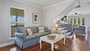 A spacious living room with a grey sectional sofa, a white coffee table, and a staircase with a black railing. - Beautifully Renovated Waterfront House in Gulfport (Gulfport)