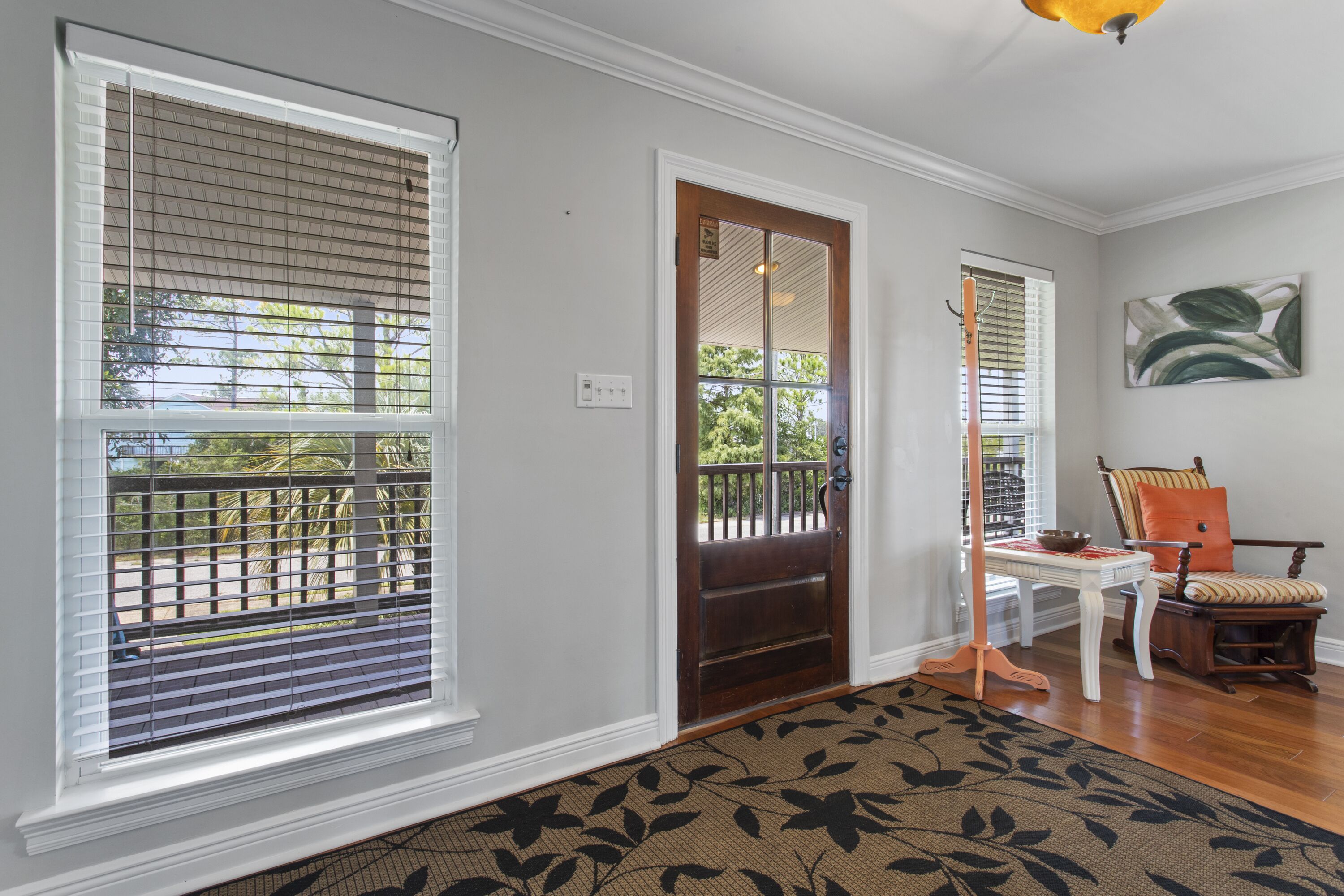 A hallway with a wooden door, a white table with a bowl, and a chair with a cushion.