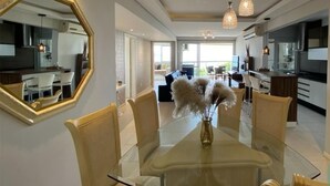 A modern dining area with a glass table, chairs, and a vase of pampas grass. - Nautilus Premium View - Penha - SC (Penha)