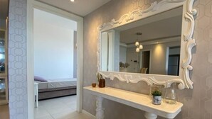 A bathroom with a large mirror, a white vanity, and a hexagonal patterned wall. - Nautilus Premium View - Penha - SC (Penha)