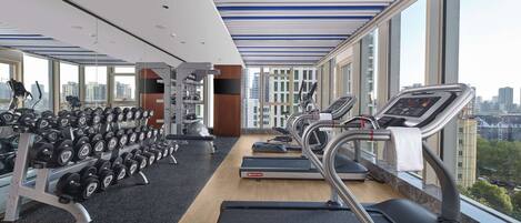 A modern gym with treadmills, dumbbells, and weight machines.