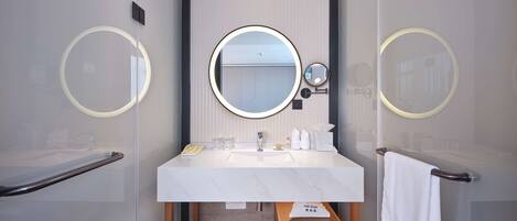 A modern bathroom with a large mirror, a white sink, and a towel rack.