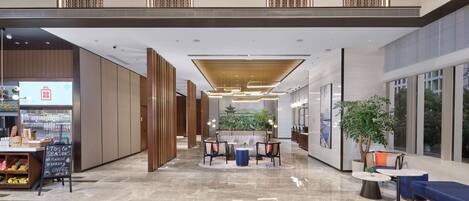 A modern lobby with a coffee shop, seating area, and a reception desk.