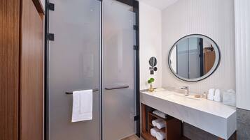 A modern bathroom with a double door, a round mirror, a vanity with a marble countertop, and a towel rack.