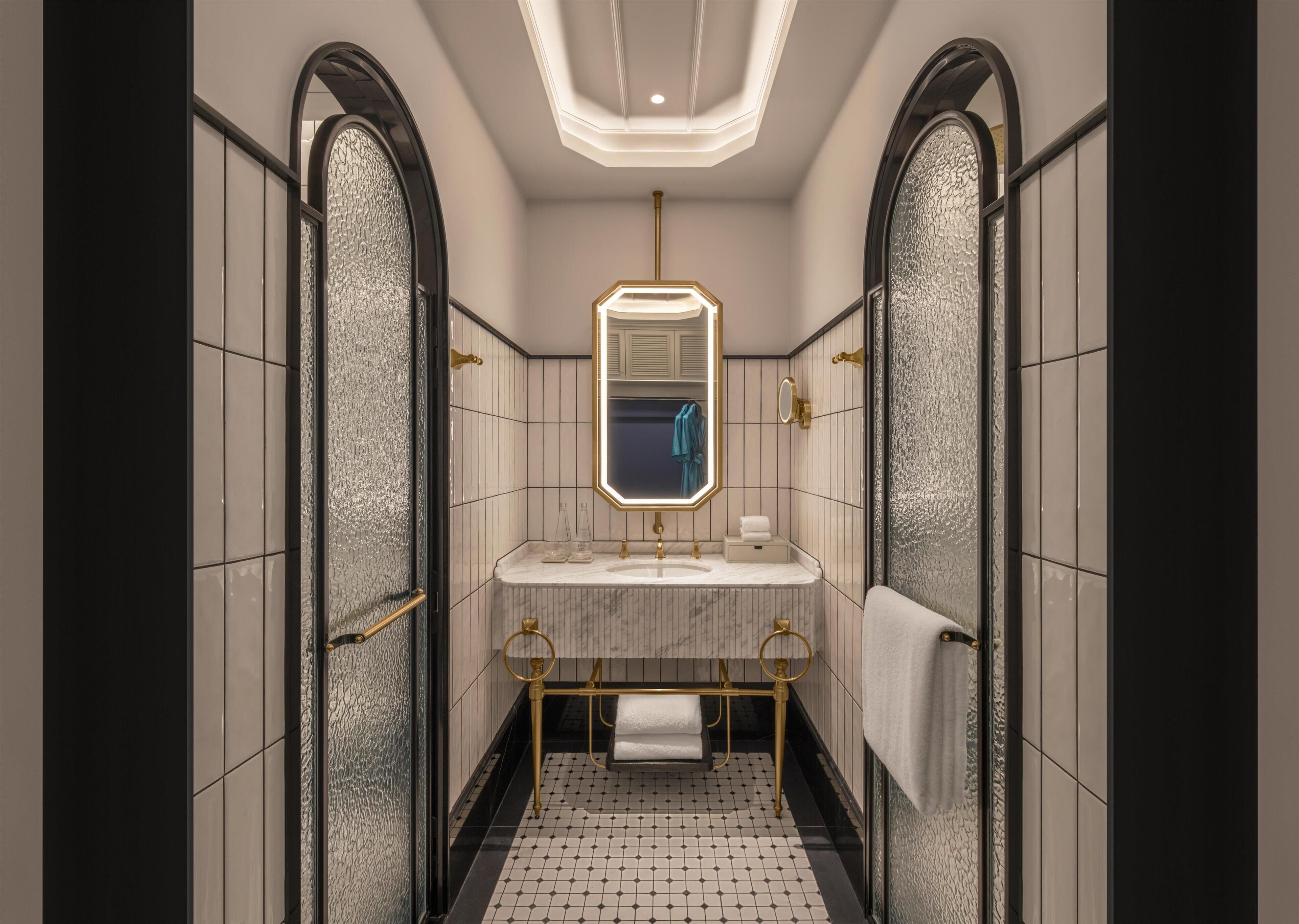 Un baño moderno con tocador de mármol, un espejo grande y un grifo dorado.