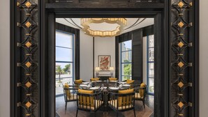 A dining area with a round table, chairs, and a chandelier.
