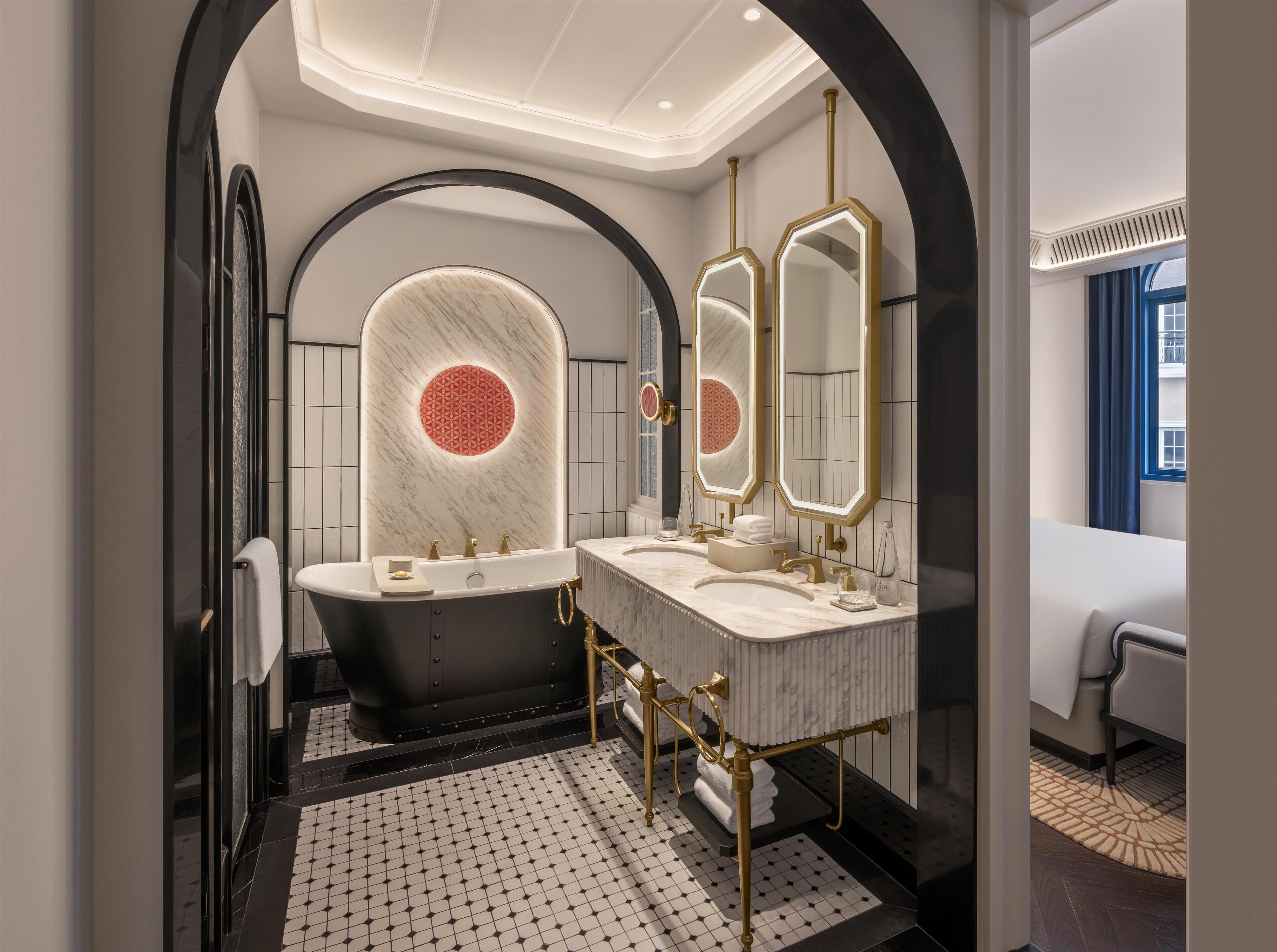 A modern bathroom with a freestanding bathtub, two sinks, and a large mirror.