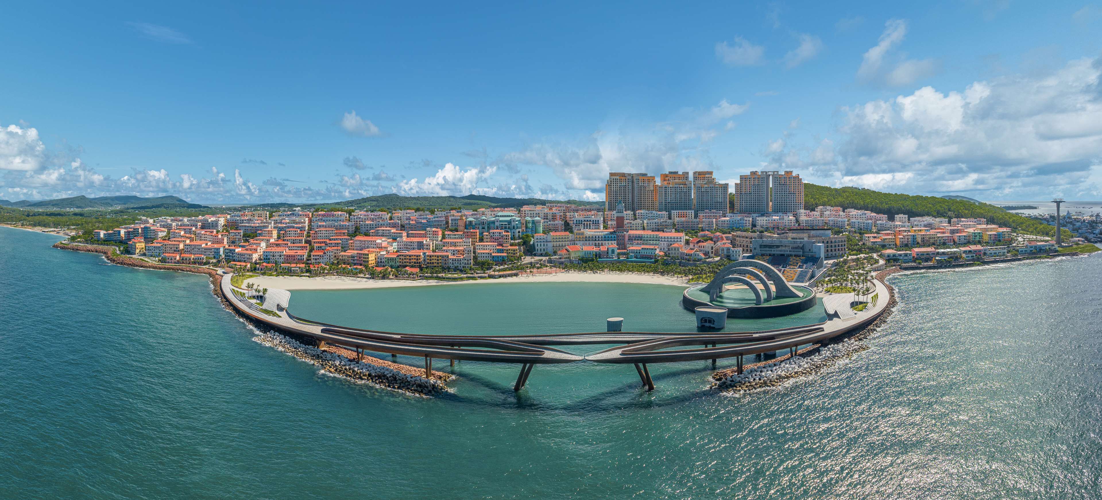 An aerial view of a coastal city with a circular park, a marina, and a mix of residential and commercial buildings.