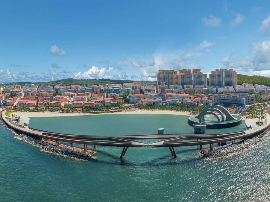 An aerial view of a coastal city with a circular park, a marina, and a mix of residential and commercial buildings.