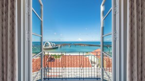 A balcony with a view of the ocean, a bridge, and a coastal town. - La Festa Phu Quoc, Curio Collection By Hilton (Phu Quoc)