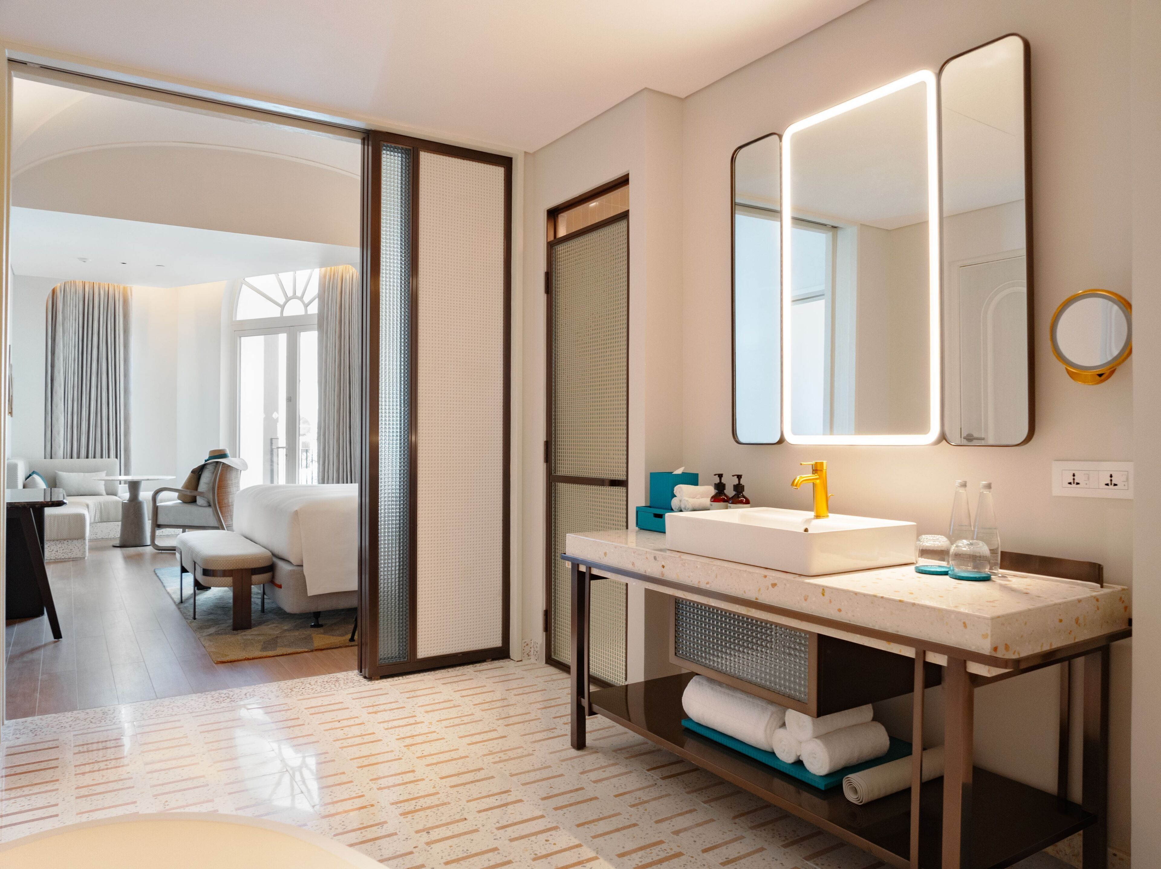 Un baño moderno con un espejo grande, un lavabo blanco y un perchero para toallas.