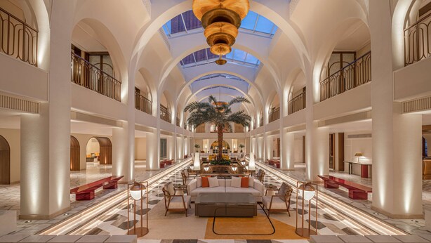 A spacious lobby with high ceilings, a central fountain, and a palm tree. - La Festa Phu Quoc, Curio Collection By Hilton (Phu Quoc)