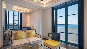 A modern living room with a sofa, armchairs, a coffee table, and a view of the sea. - La Festa Phu Quoc, Curio Collection By Hilton (Phu Quoc)