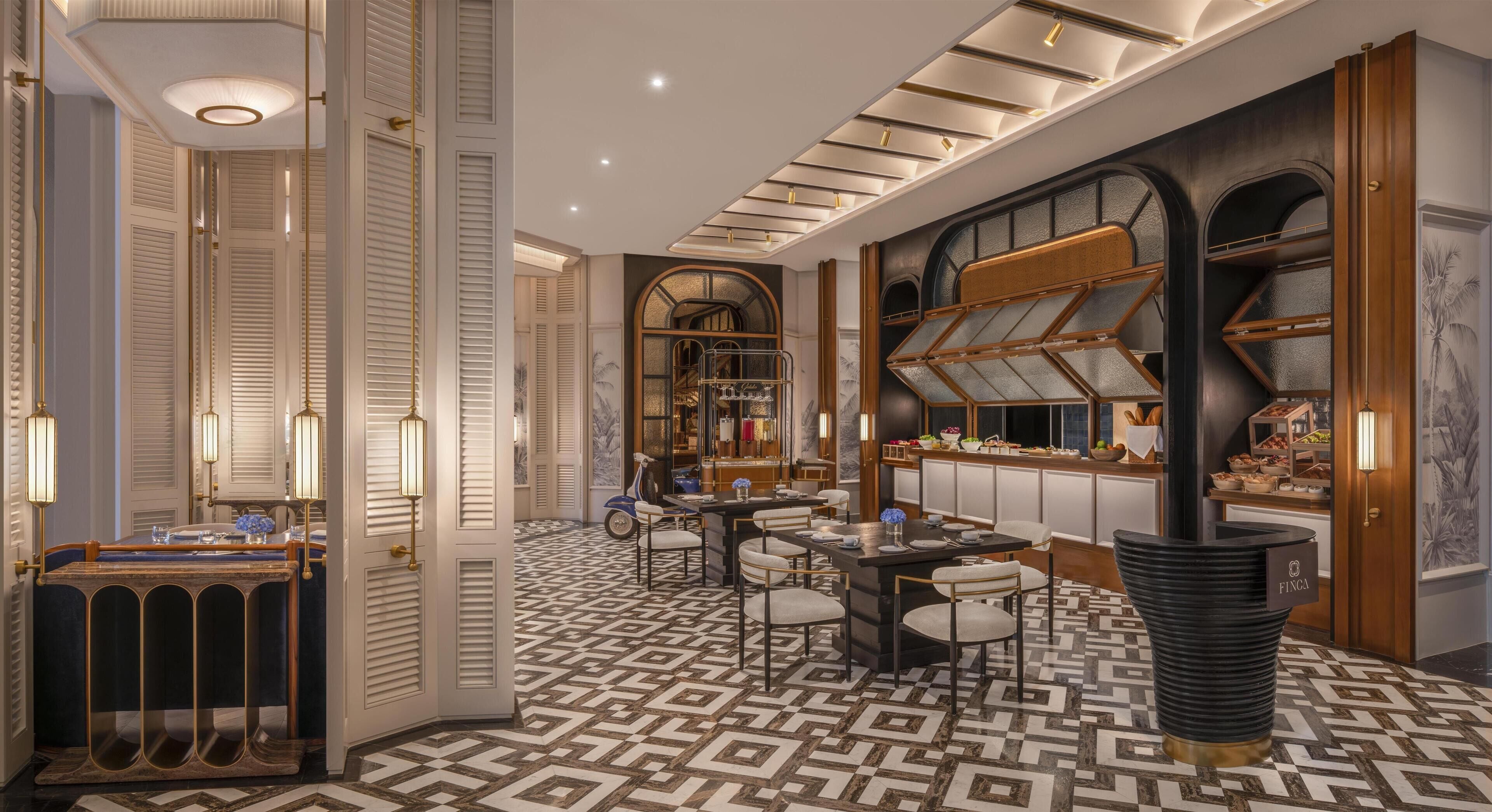 A luxurious hotel lobby with a patterned floor, a reception desk, and a dining area.
