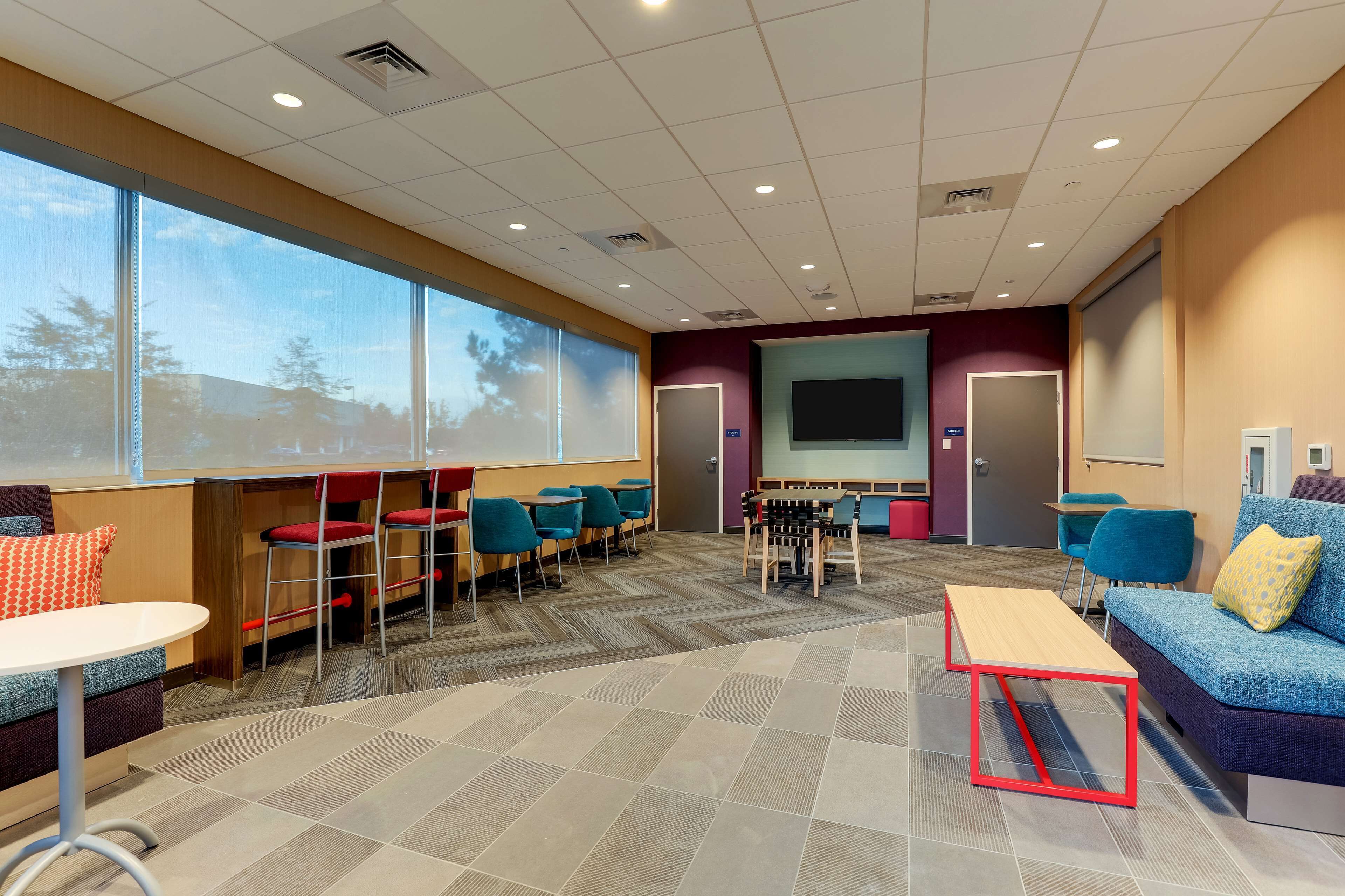 A conference room with a large screen, multiple tables and chairs, and a sofa with a projector screen.