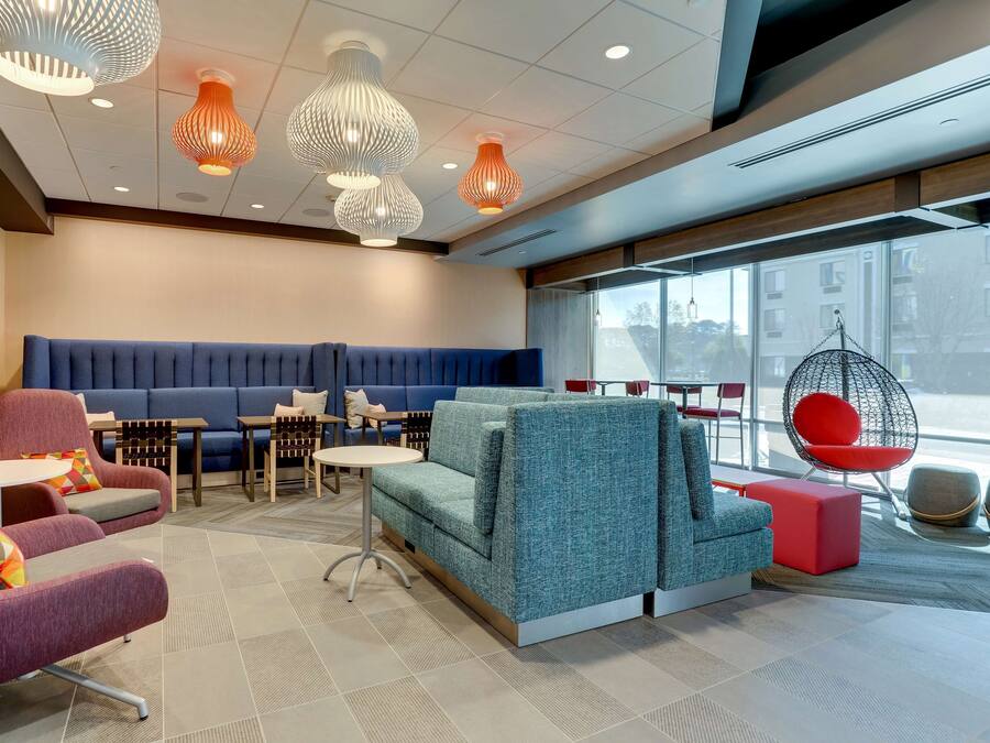 A modern lounge area with seating arrangements, including sofas and chairs, and a seating area with a blue cushioned bench.