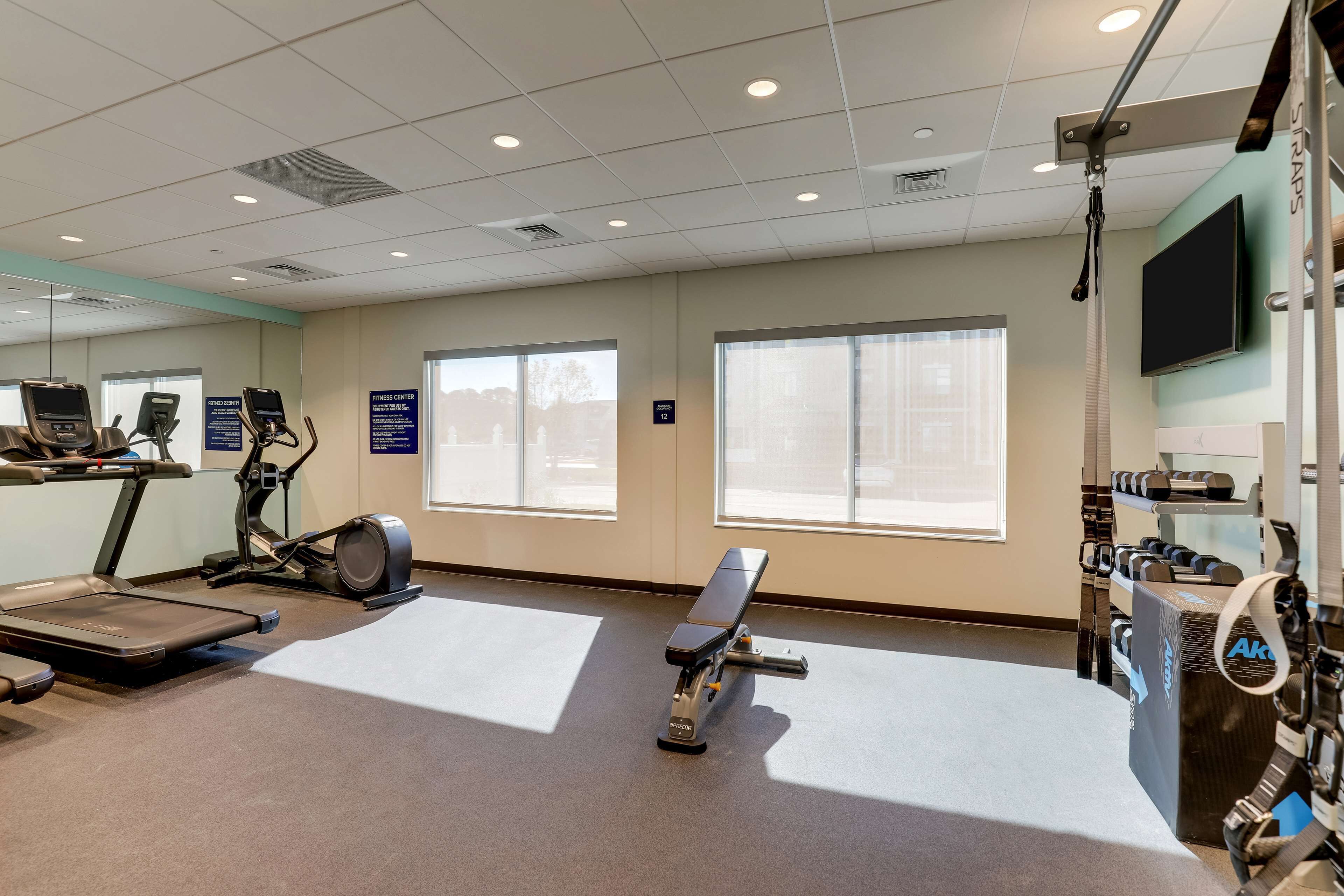 A fitness center with treadmills, a bench, and weightlifting equipment.