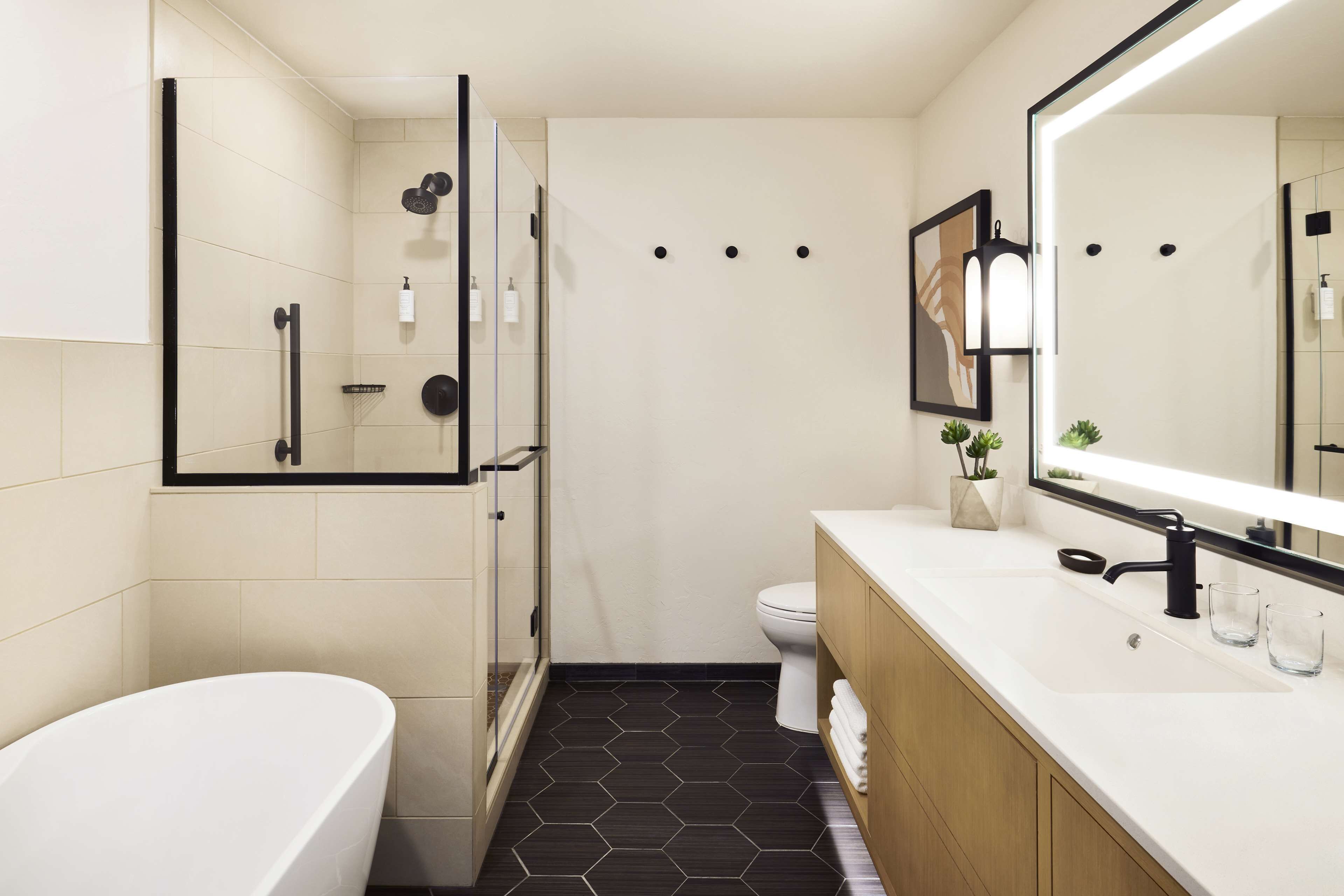 A modern bathroom with a freestanding bathtub, a glass-enclosed shower, a toilet, and a vanity with a large mirror.