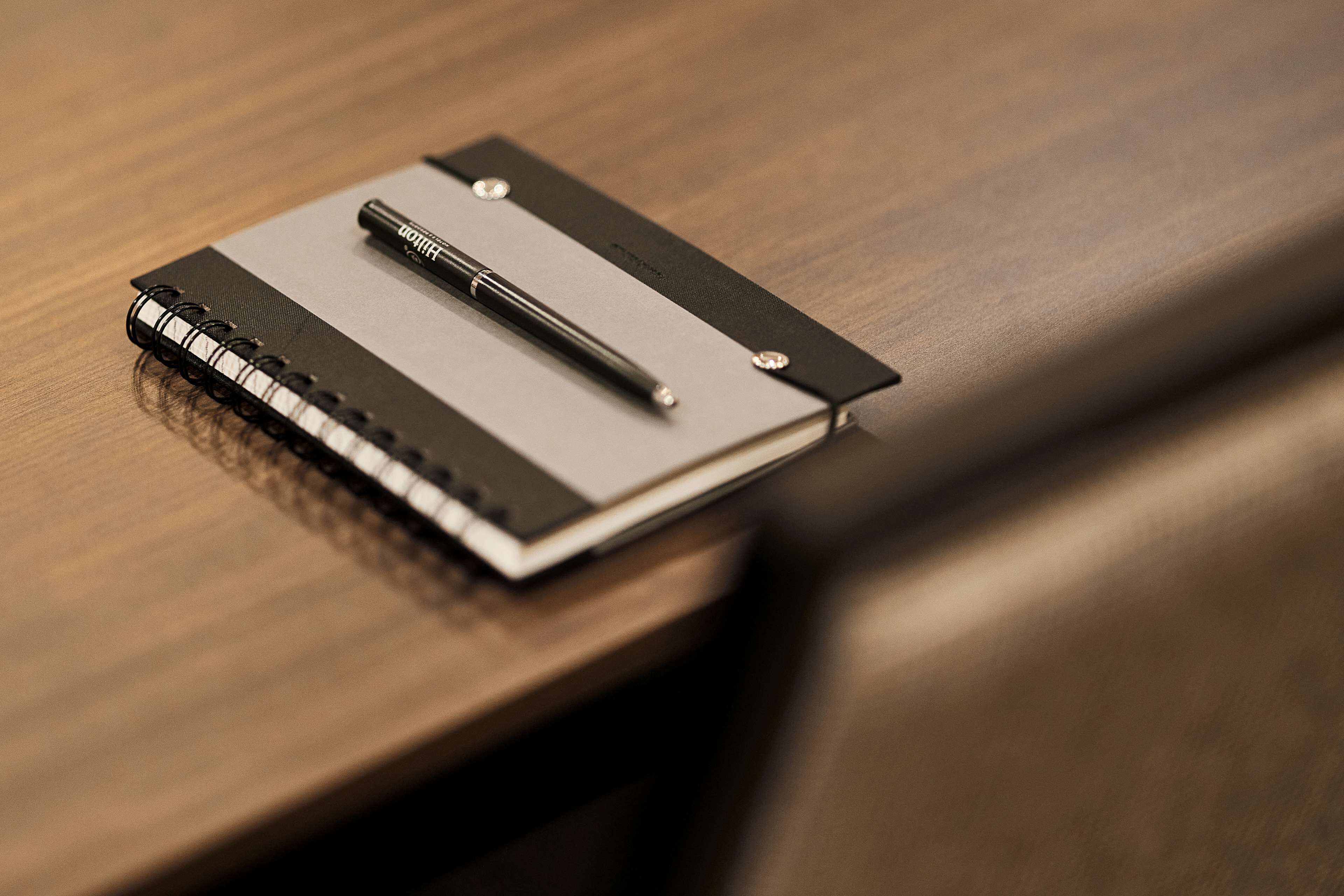 Een notitieboekje met een pen op een houten tafel.