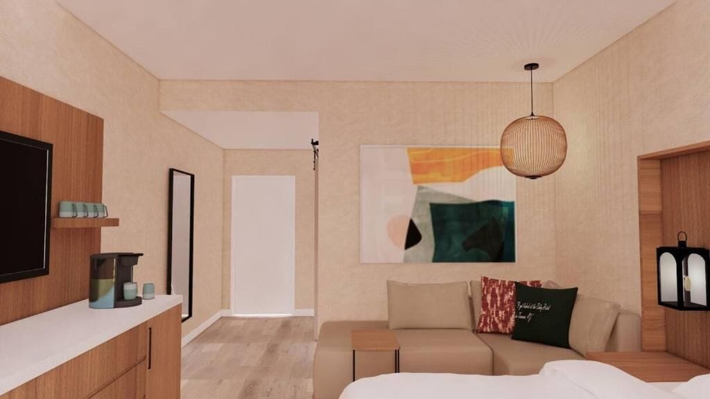 A modern hotel room with a bed, a sofa, a TV, a coffee machine, and a painting on the wall.