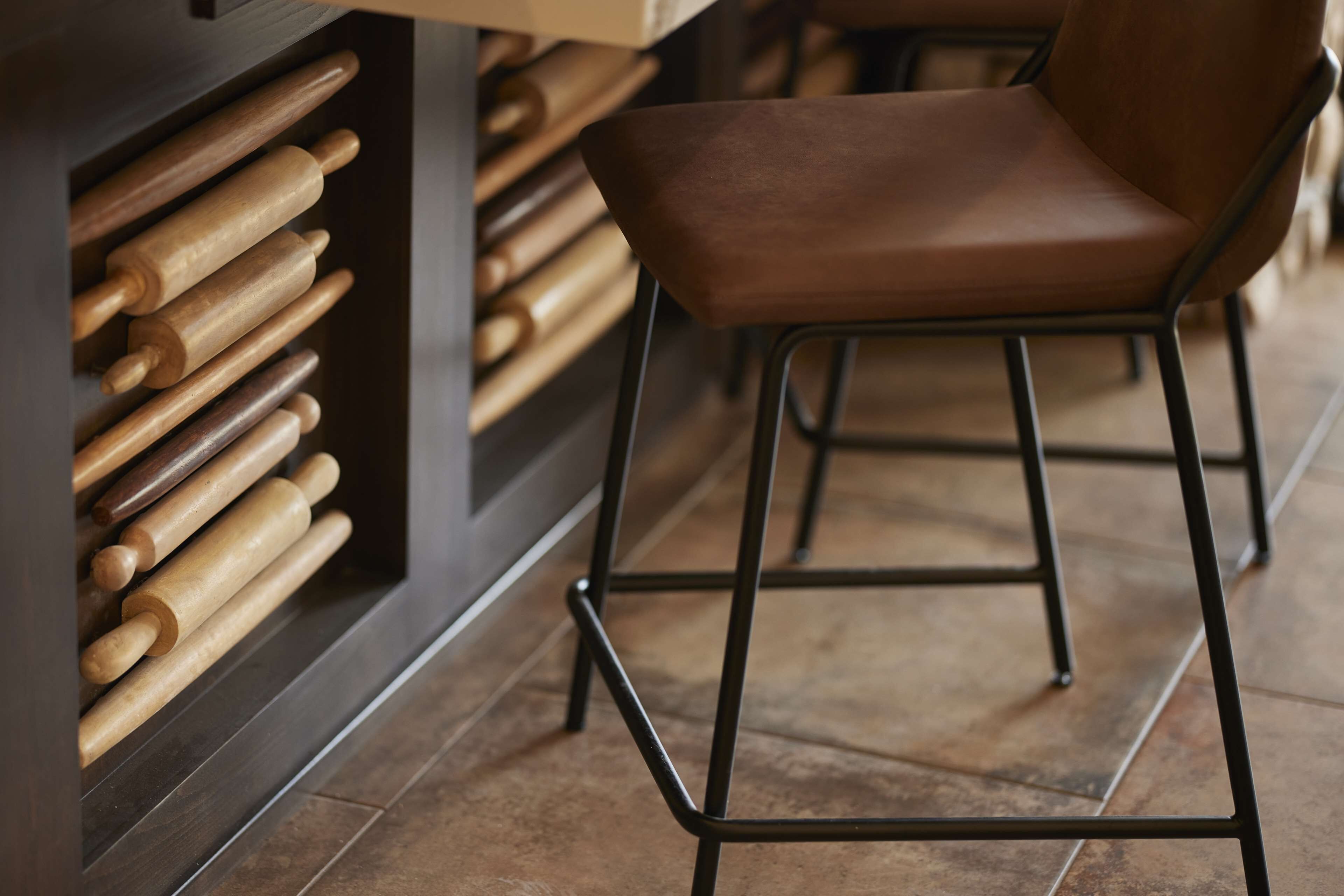 A kitchen with wooden rolling pins and a brown leather chair.