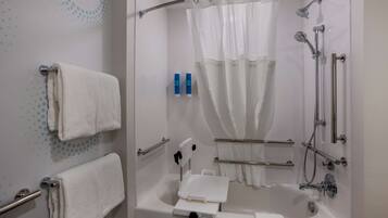 A modern bathroom with a bathtub, shower, and handrails.