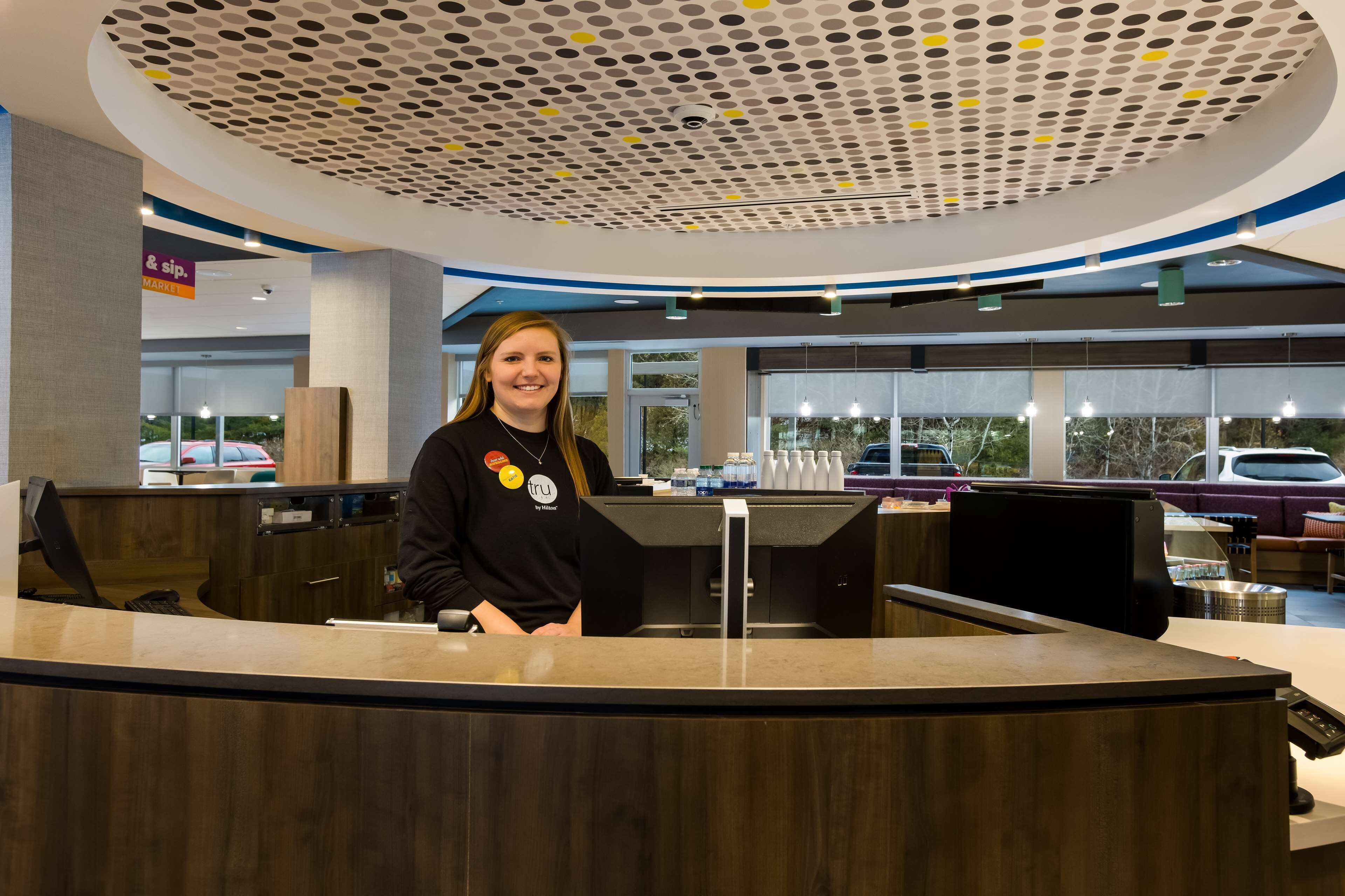 A reception desk with a modern design, including a circular ceiling with a dot pattern and a sign for 'SIP Market' in the background.