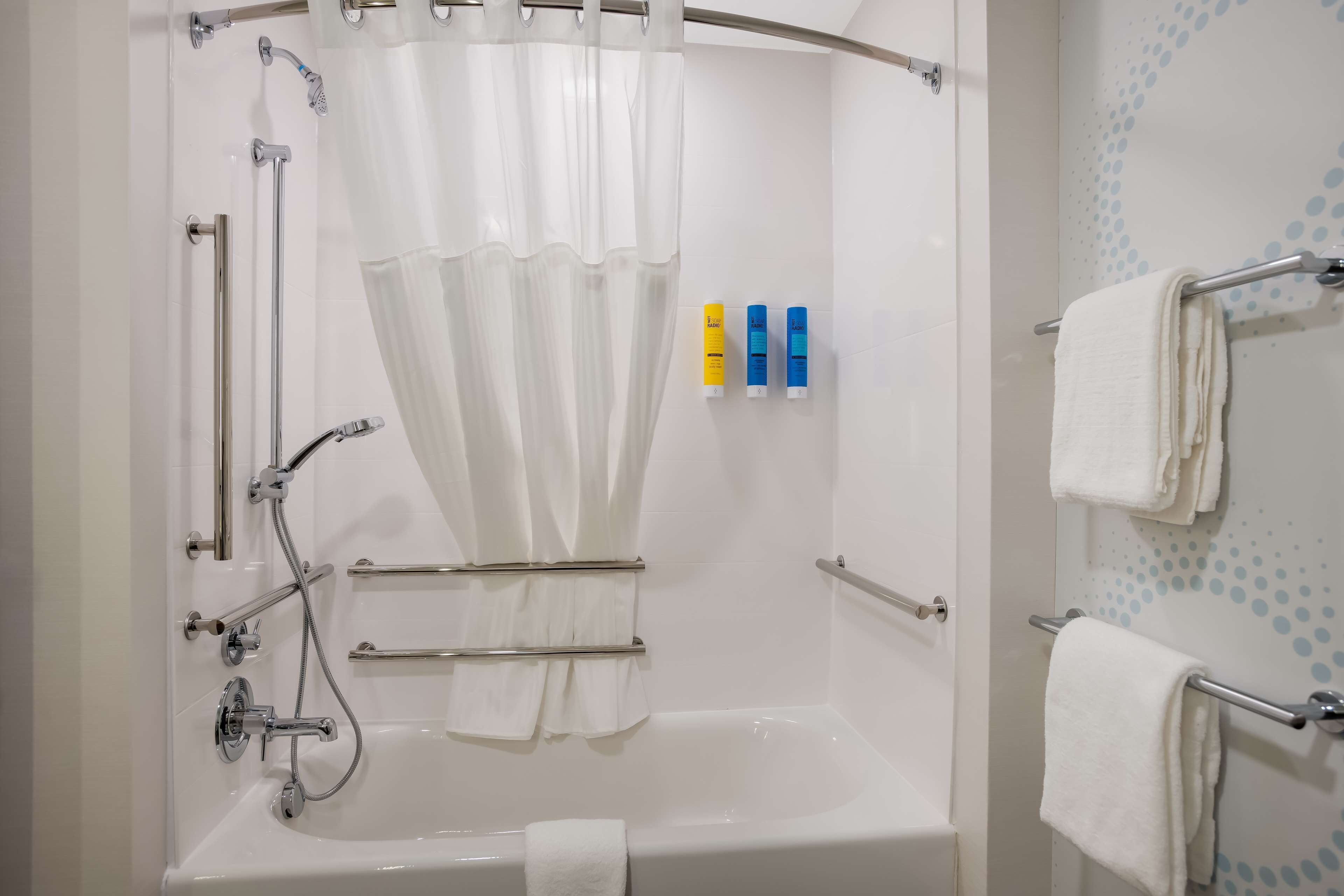 Un baño moderno con bañera, ducha y barras de apoyo.